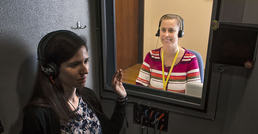 Laura Burger performs a hearing test in soundproof booth