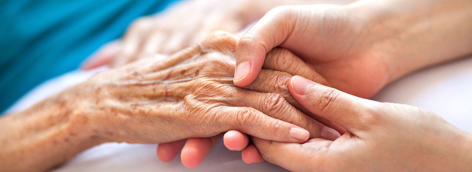 Elderly hand clasped with younger hands