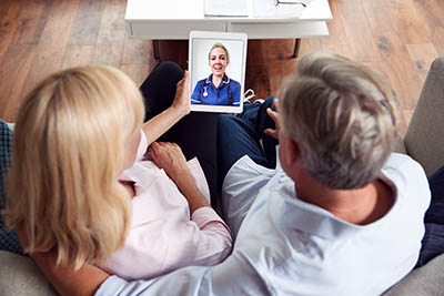 Couple viewing a tablet showing a female provider.