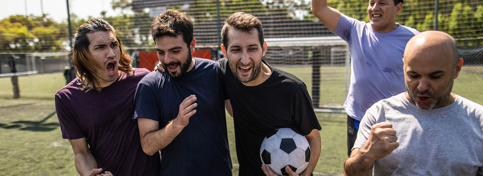 Group of men playing soccer and celebrating.