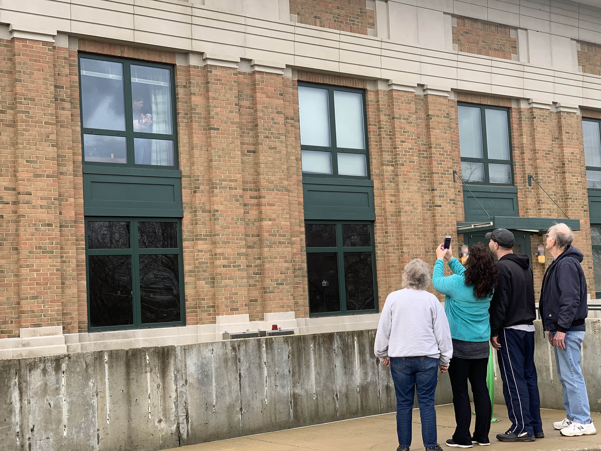 A family takes pictures of a father holding a newborn baby in the window at Columbus Regional Hospital.