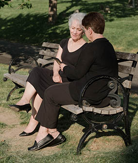 Woman consoling another on a park bench.